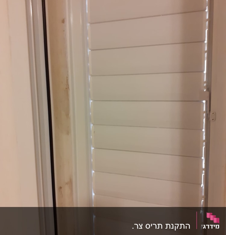 תריסי אלומיניום לבנים במסגרת חלון